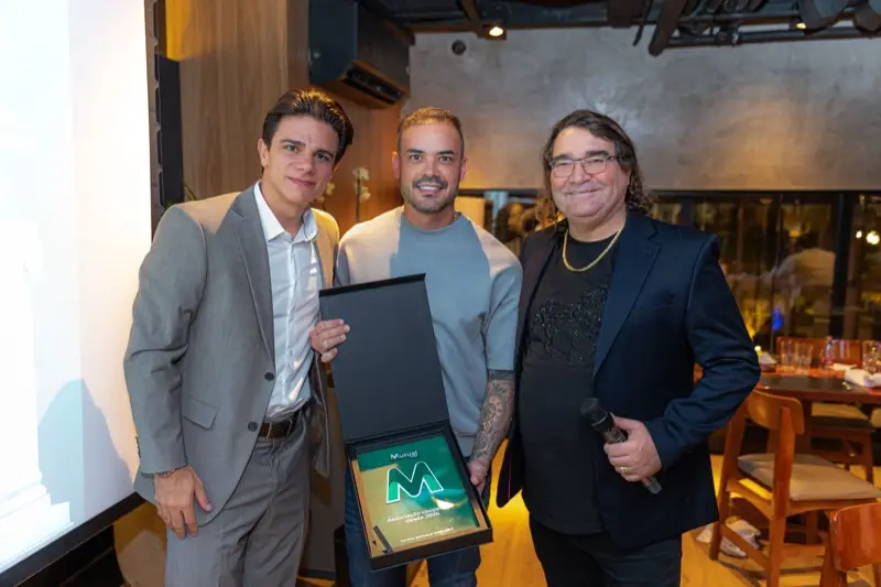 Três participantes posam com a placa de reconhecimento da Mutualcoop entregue no encontro.